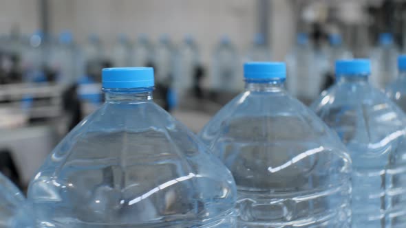 Close-up of five-liter water bottles moving along the conveyor