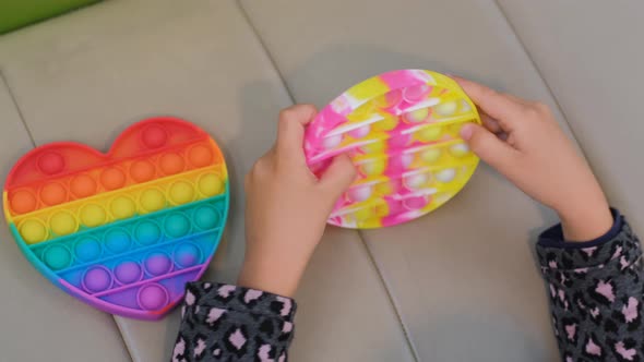 Child Girl Plays with Colorful Pop It Fidget Toy