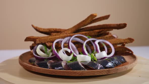 Tasty bread sticks on a plate with salted fish and onion