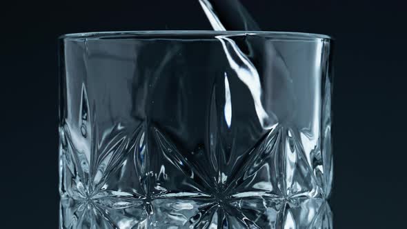 Closeup Water Pouring Glass with Splashing Dark Background