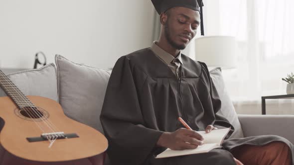 Male African Graduate Making Notes in Notebook