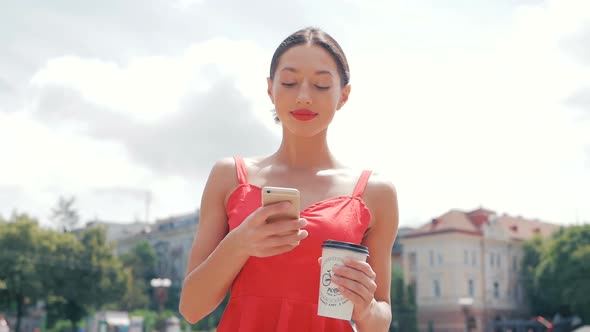 Portrait of a young beautiful trendy woman in red walking around the city, drinking coffee, talking