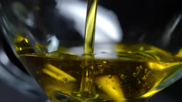 Closeup Transparent Jar Bottom with Yellow Golden Sunflower Oil Pouring in Slow Motion