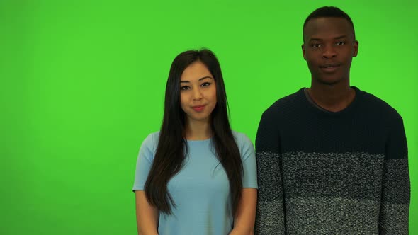 A Young Asian Woman and a Young Black Man Applaud and Nod Their Heads - Green Screen Studio