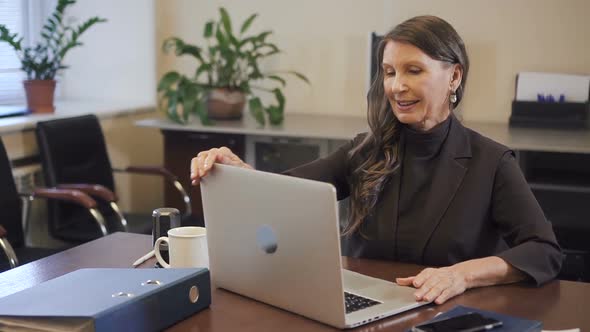 Experienced Mature Businesswoman Finishing Working on Laptop Computer in Office