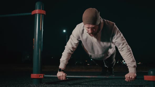 Man Is Doing Push-ups Outdoors in Sports Area in Night Time