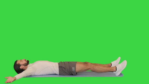 Man Making Abdominal Exercises on a Mat on a Green Screen Chroma Key