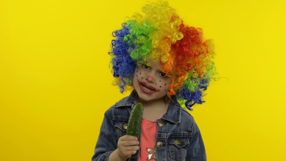 Little Child Girl Clown in Colorful Wig Making Silly Faces, Singing, Smiling, Dancing. Halloween