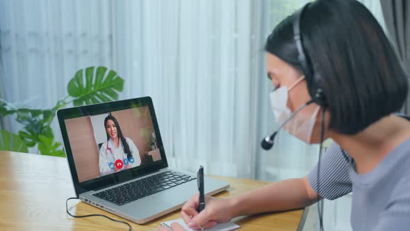 Asian young woman patient use laptop virtual video call with doctor in living room at home.