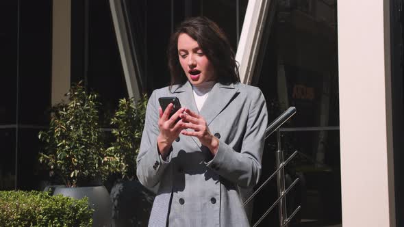 Happy Woman Using Phone Woman Has Good News Celebrates Victory in the Street