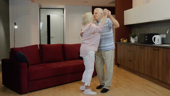 Happy Carefree Elderly Senior Grandparents in Love Dancing Waltz in Modern Living Room at Home