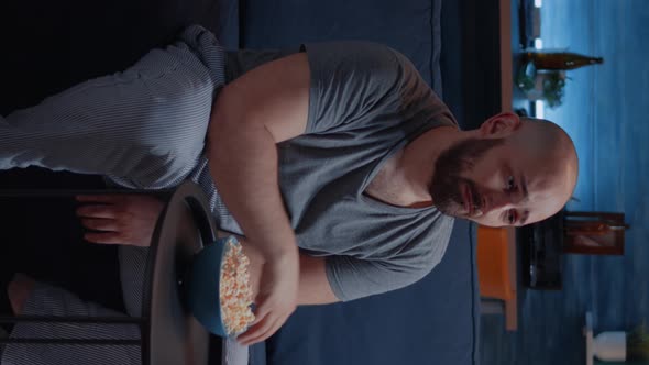 Vertical Video Focused Man Looking at Drama Movie Crying Sitting on Sofa Eating Popcorn