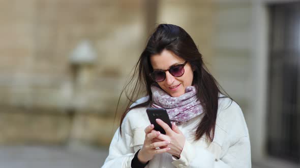 Beautiful Smiling Businesswoman Enjoying Break Using Smartphone Outdoor at Sunny Day Medium Closeup