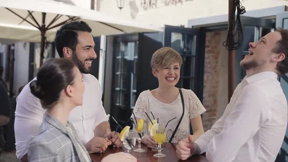 Young People Drinking Cocktails At City Street Cafe