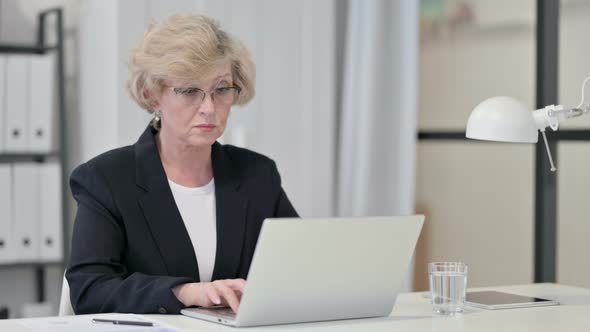 Old Businesswoman Using Laptop at Work