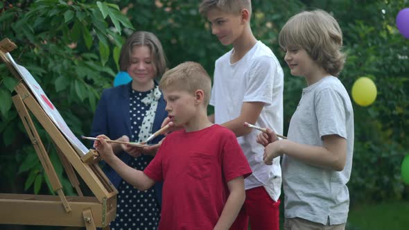 Children Drawing with Brushes in Slow Motion Talking Smiling Standing at Easel Outdoors