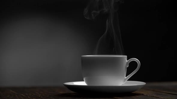 Cup of Coffee on a Wooden Table Against the Black and Grey Background. Steam Is Coming From the Cup