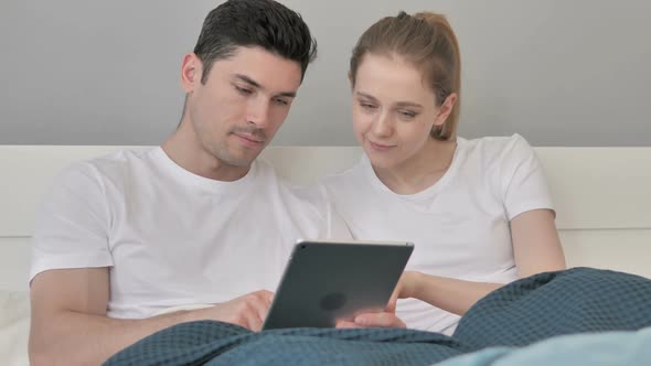 Couple Using Tablet in Bed