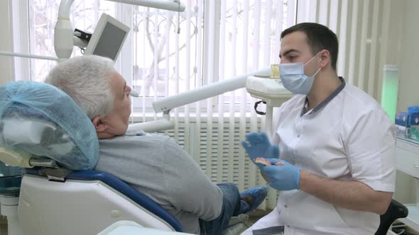 Elderly Patient Consulting with Dentist About Removable Dentures in Dental Clinic