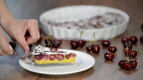 Piece of homemade yummy clafoutis pie with cherries on white plate