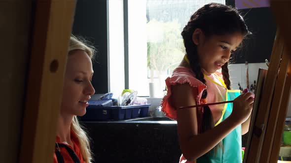 Teacher assisting schoolgirl in drawing class