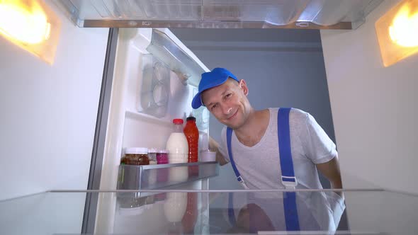 refrigerator repairman opens door and shows class by giving a thumbs up.