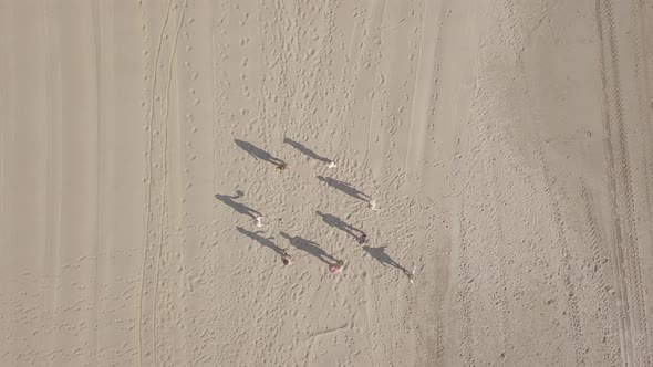 Aerial view of children teenagers play ball on the sandy beach by the sea, summer vacation. Zoom out