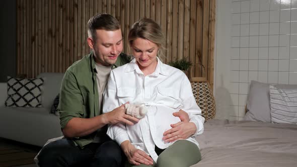 Man Hand Steps Fingers with Socks Across Pregnant Lady Belly