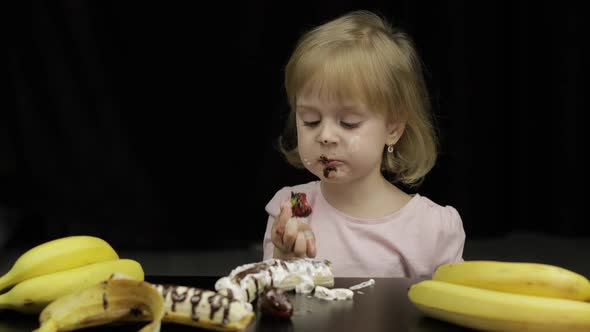 Child Eats Banana, Strawberry with Melted Chocolate and Whipped Cream