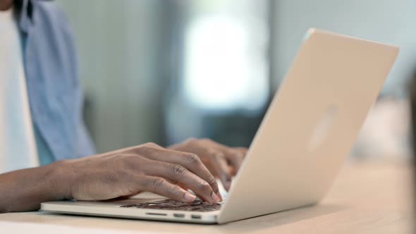 Hands of African Man Typing on Laptop Keyboard