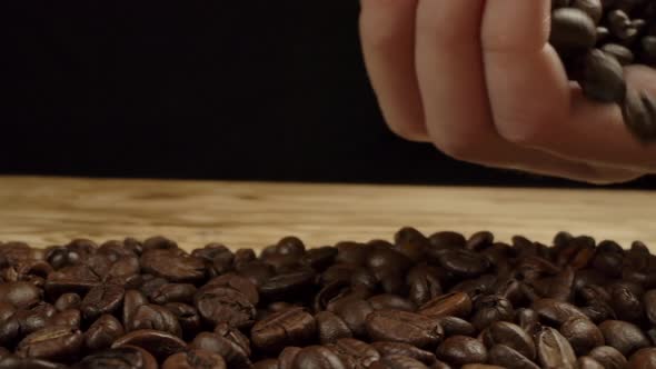 Woman's Hand Scatters Coffee Beans on the Table