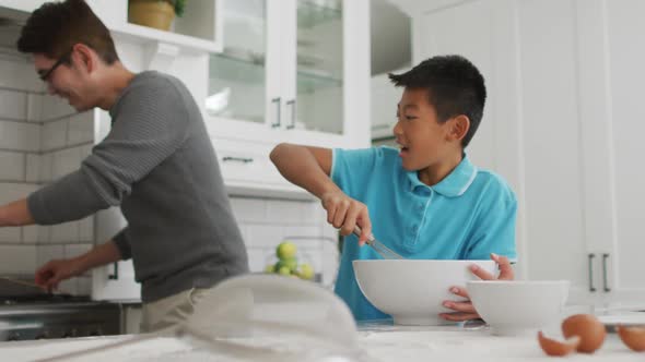 Happy asian father in kitchen making breakfast with laughing son and daughter