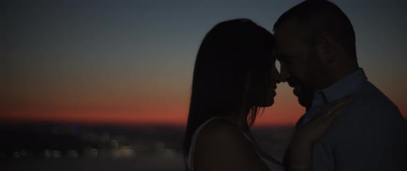 Silhouette of a couple standing close to each other, smiling, feeling happy 