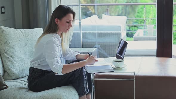 Beautiful Girl on the Couch Working on a Laptop