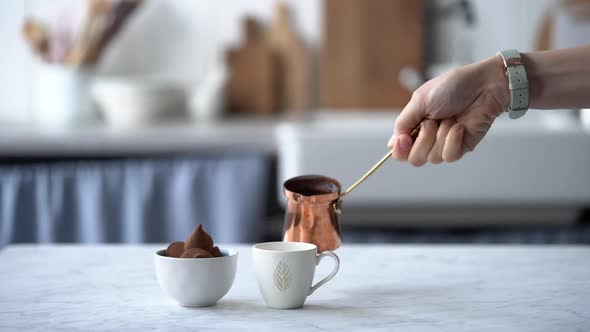 Woman pouring coffee from turk into cup