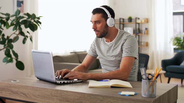 Man in Headphones with Laptop Working at Home