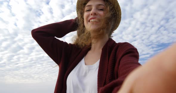 Low angle view of young beautiful caucasian woman in hat smiling an looking at camera 4k