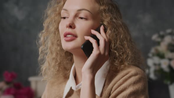 Close Up of a Young Caucasian Woman Shy Talking on a Phone Indoors