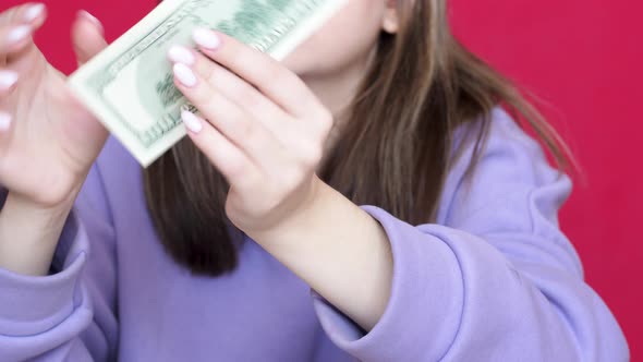 Portrait of a Caucasian young woman 20-22 years old holding a bill of 100 American dollars. A girl i