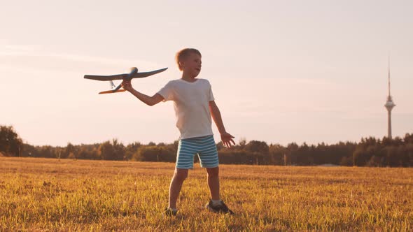 Little boy plays with a toy plane in a field at sunset. Childhood, freedom, inspiration concept.