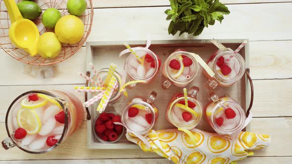 Raspberry lemonade garnished with fresh lemon and raspberries in drinking mason jars.