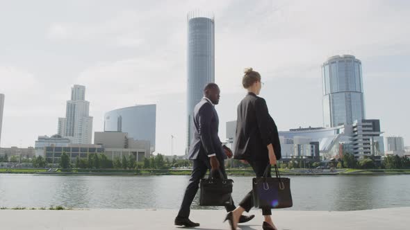 Diverse Business Couple Walking Along River