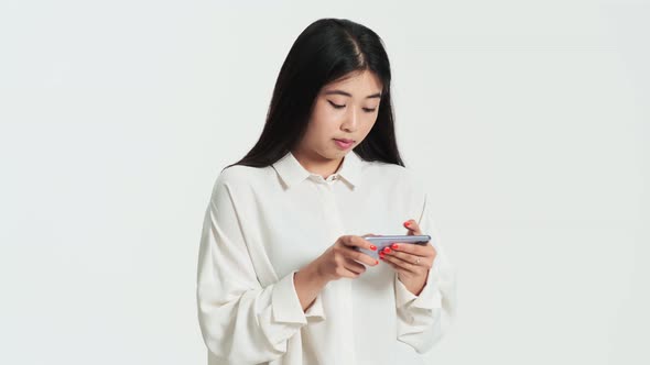 Focused asian korean woman playing games on her phone