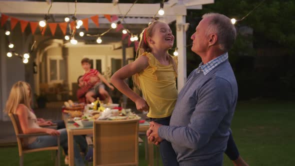 Grandfather carrying his granddaughter outdoors