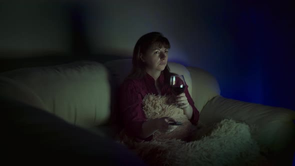 Woman with a Glass of Wine Sits at Home on the Sofa in the Evening and Watches Tv Deep Feelings