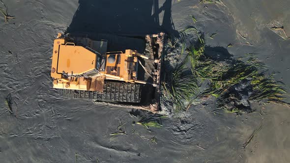 Aerial View on Top Large Bulldozer Cleans the Bottom of the Lake From Thickets and Swamps