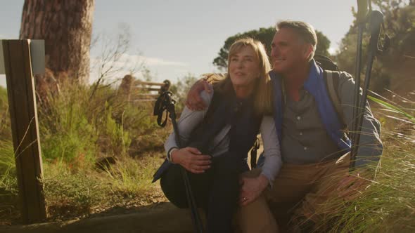 Active senior couple sitting on the floor in forest