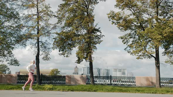 Side View of Fit Young Lady in Sports Clothing Jogging Outdoors in Urban Park