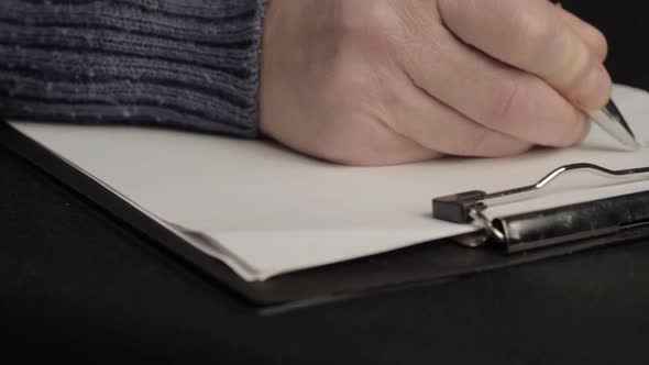 Busy person writing up notes on a clipboard close up