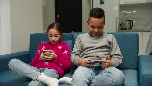 Multiethnic Children Using Smartphones Sitting on Couch at Home